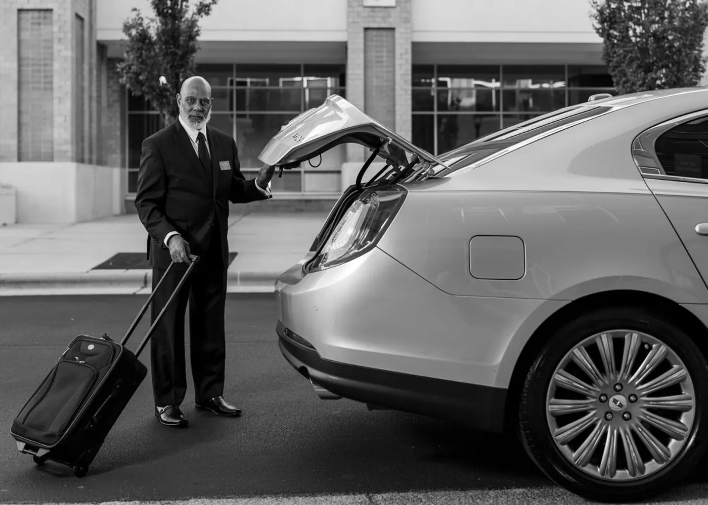 Chauffeur loading a suitcase into the boot of a sedan