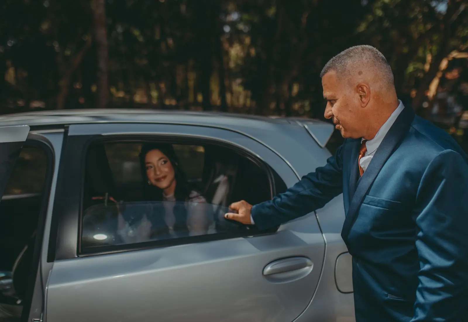 Driver holding the rear door open for a passenger
